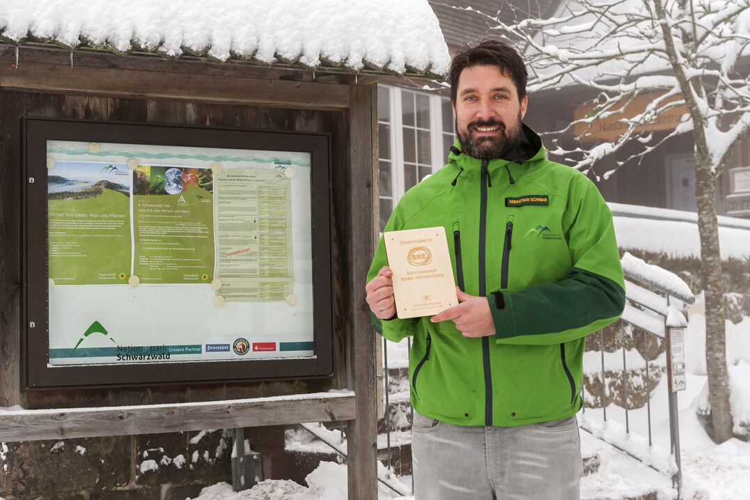 Sebastian Schwab, Leiter der Wildnisbildung im Nationalpark, vor der Plakette zur Ehrenmitgliedschaft im neuen BNE-Schulnetzwerk